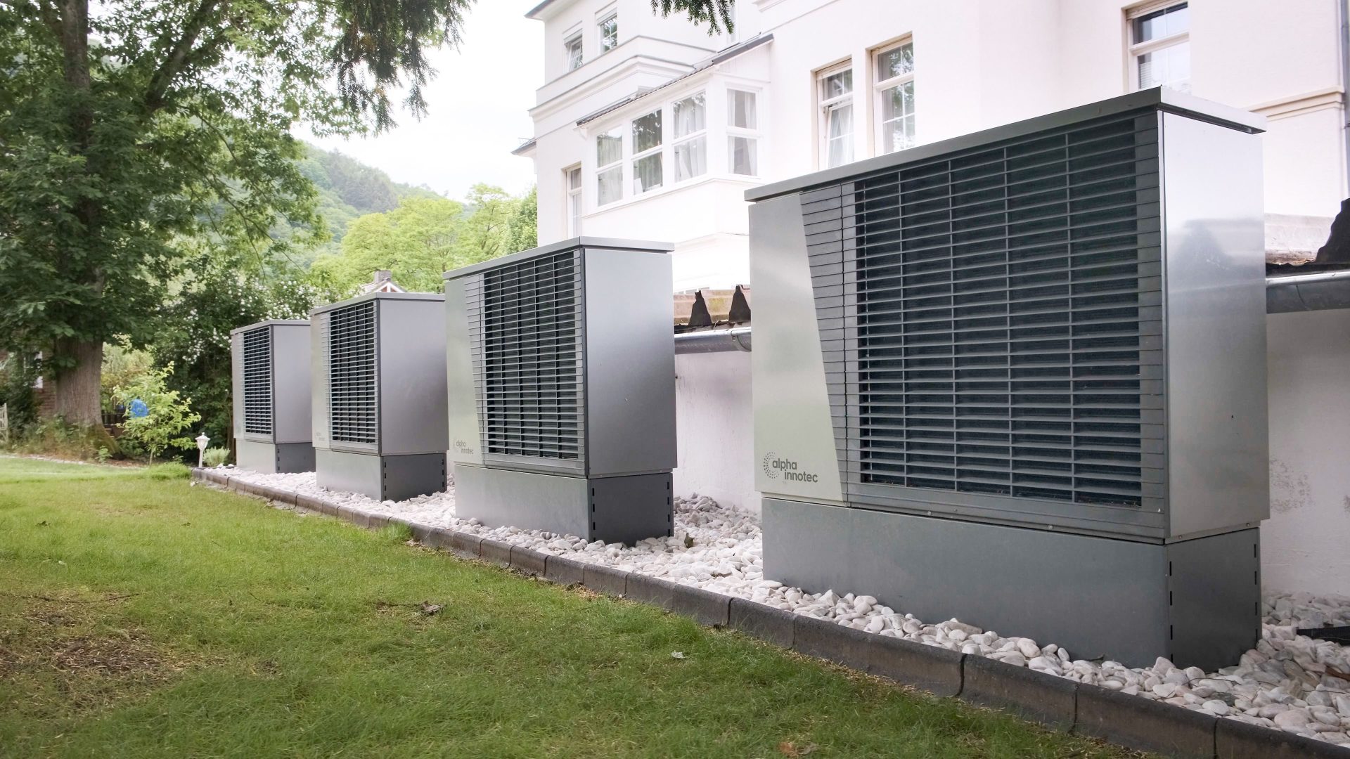 Reihe von Wärmepumpen vor einem Gebäude, die für nachhaltige Energielösungen werben.