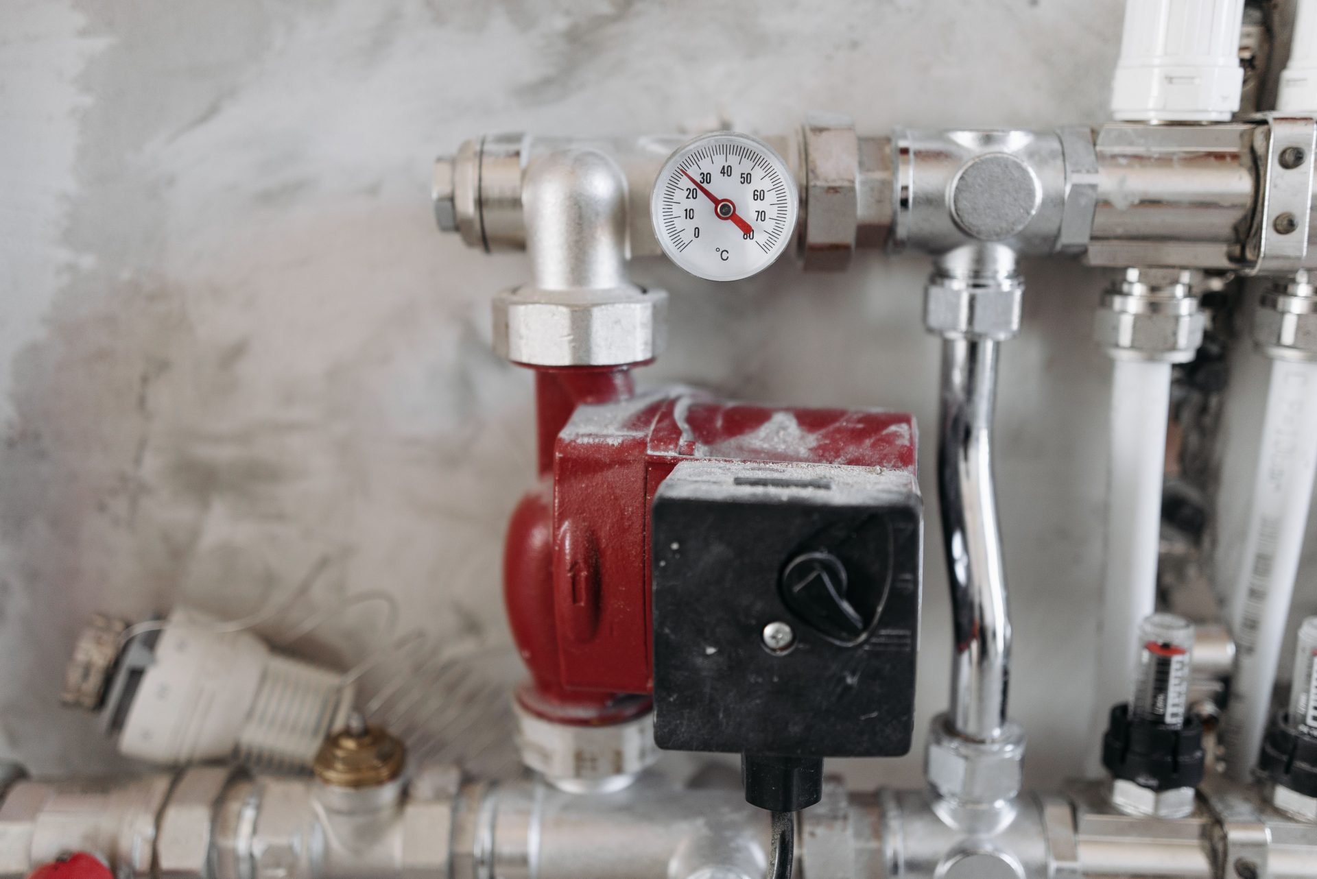 Nahaufnahme eines industriellen Rohrleitungssystems mit Manometer und Stahlrohren.