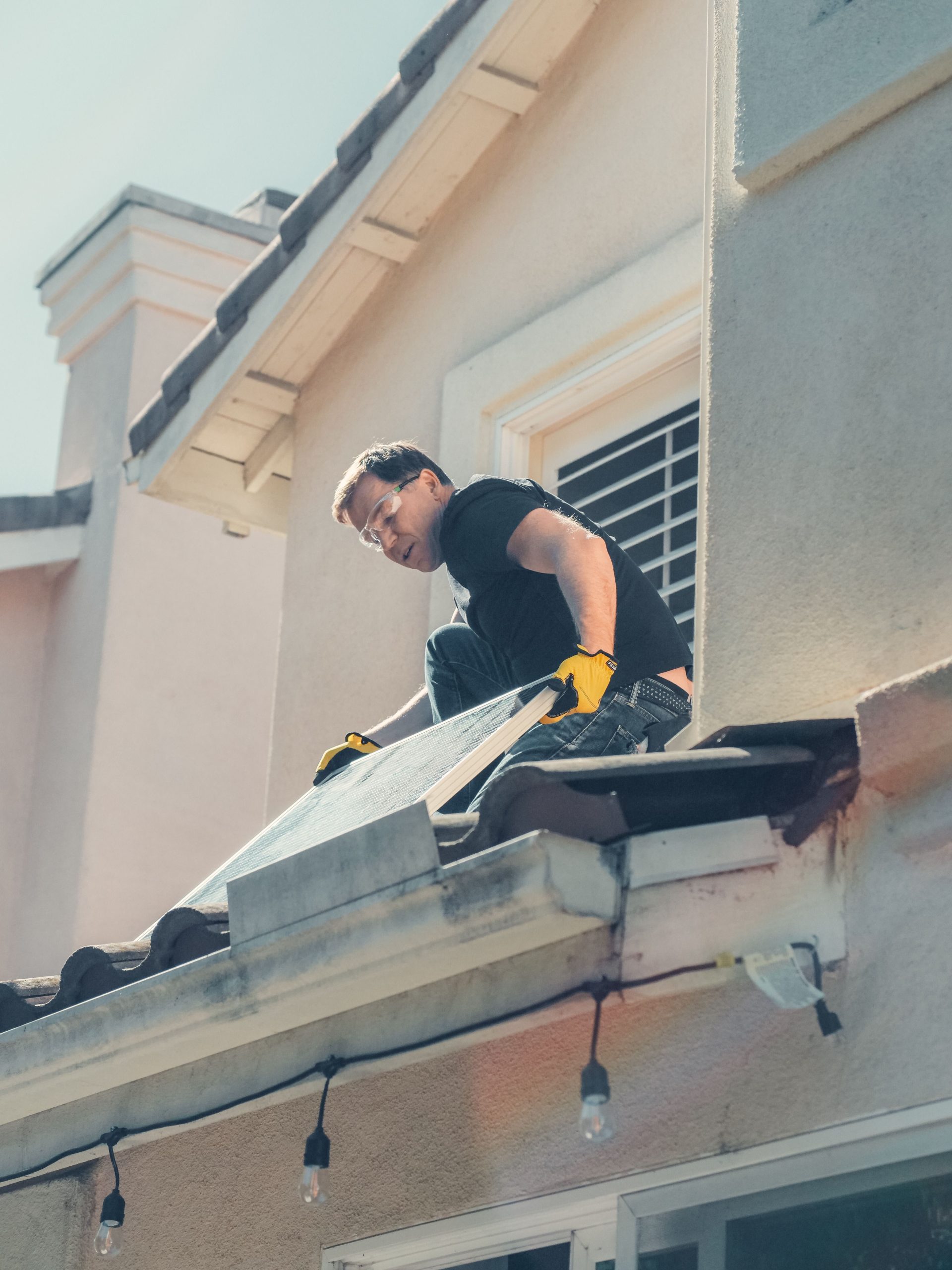 Ein Arbeiter installiert Solarmodule auf dem Dach eines Wohnhauses und fördert so saubere Energie.